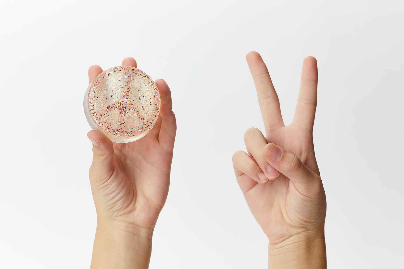 Two hands, one holdings a sparkle soap in a peace sign, the other hand holding up two fingers in the peace sign.